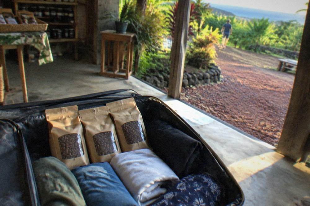 Bags of Kona coffee packed inside an open suitcase in a farm shop